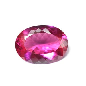 Peut inclure: Une pierre précieuse de forme ovale avec un dégradé de couleurs rose et magenta. La gemme a une surface à facettes, reflétant la lumière et mettant en valeur sa clarté. La pierre est posée sur un fond blanc.