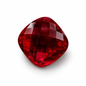 May include: A vibrant, deep red gemstone with a cushion cut and a faceted surface. The stone features a square shape with rounded corners and exhibits a high level of clarity, reflecting light across its many polished, geometric facets.