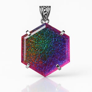 Puede incluir: Un colgante hexagonal con una gema iridiscente. La gema muestra un espectro de colores, incluyendo rojo, verde y morado. El colgante está engastado en metal plateado con una fianza decorativa.