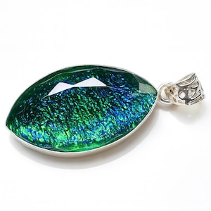 May include: A dichroic glass pendant with a silver-colored bail. The pendant is an elongated oval shape, with a faceted top. The glass has a green and blue iridescent finish. The bail has a decorative openwork design.