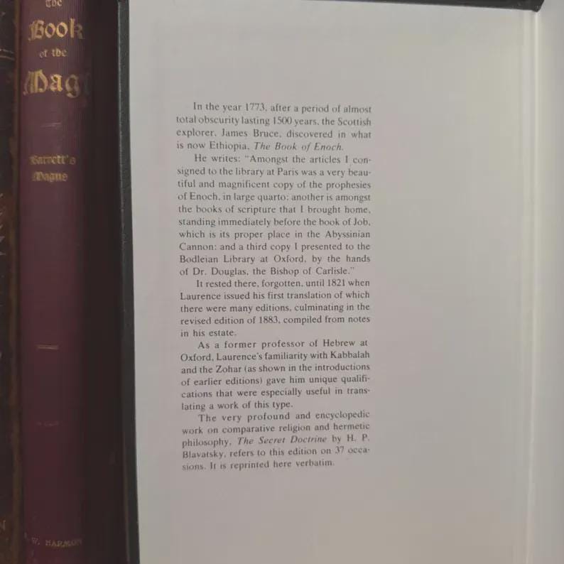 May include: An open book with text on a white page, featuring a passage about the discovery of "The Book of Enoch" by James Bruce in 1773. The text is in black font. The book is next to a dark book.