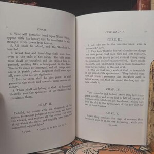 May include: Open book with text from the Book of Enoch, featuring chapters and verses. The pages are aged, with a cream-colored hue and black text. The book is open to reveal the text.