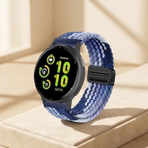 Könnte beinhalten: Eine schwarze Garmin Smartwatch mit einem blau-weiß geflochtenen Armband. Das Zifferblatt zeigt die Uhrzeit 10:10 Uhr und das Datum Sa 01 an. Das Armband wird mit einem schwarzen Verschluss befestigt.