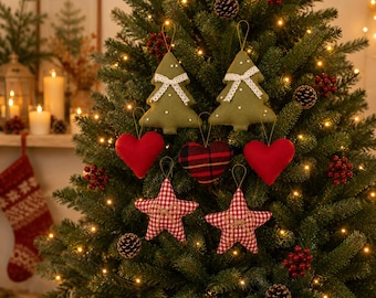 May include: A collection of fabric Christmas tree ornaments hanging on a green tree. The set includes two olive green felt trees with white lace bows, two solid red hearts, one red and black plaid heart, and two red and white gingham stars.