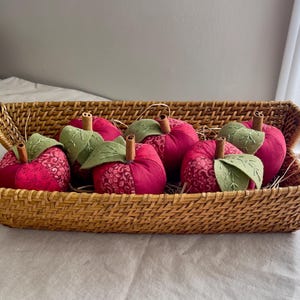 Basket filled with handmade red patchwork fabric apples with embroidered felt leaves and cinnamon stick stems.