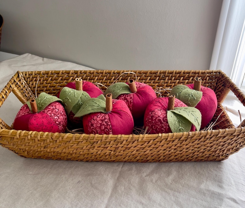 Basket filled with handmade red patchwork fabric apples with embroidered felt leaves and cinnamon stick stems.