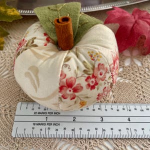 Cream patchwork fabric apple shown with ruler for size reference.