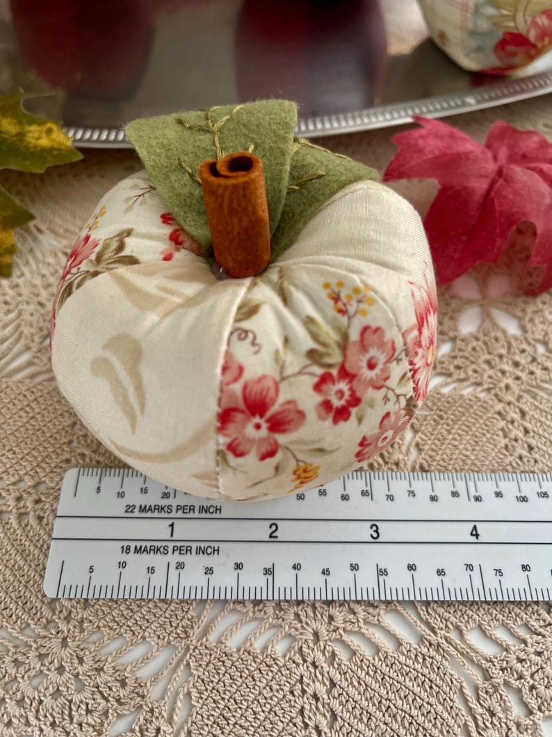 Cream patchwork fabric apple shown with ruler for size reference.