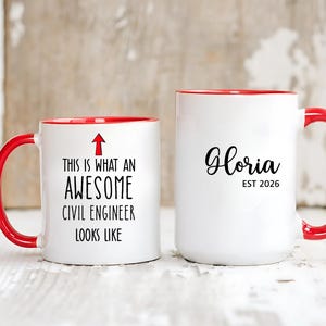 May include: Two white ceramic mugs with red handles and rims. One mug reads "THIS IS WHAT AN AWESOME CIVIL ENGINEER LOOKS LIKE" with an arrow. The other mug says "Gloria EST 2026" in black script.