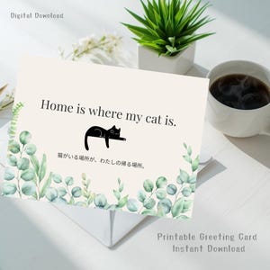 以下が含まれることがあります： 「Home is where my cat is」のテキストが入った印刷可能なグリーティングカード。テキストの下には黒猫のイラストがあります。カードは水彩画のユーカリの葉で装飾されており、上部には「Digital Download」の文字があります。