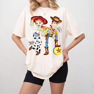 May include: A white ceramic mug with a black handle and the text "But First, Coffee" in a black, bold font. The mug is on a white surface.