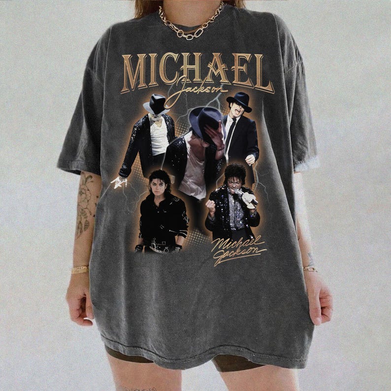 May include: Dark gray t-shirt featuring multiple images of Michael Jackson with the text "MICHAEL Jackson" in gold lettering. The shirt has a vintage, distressed look.