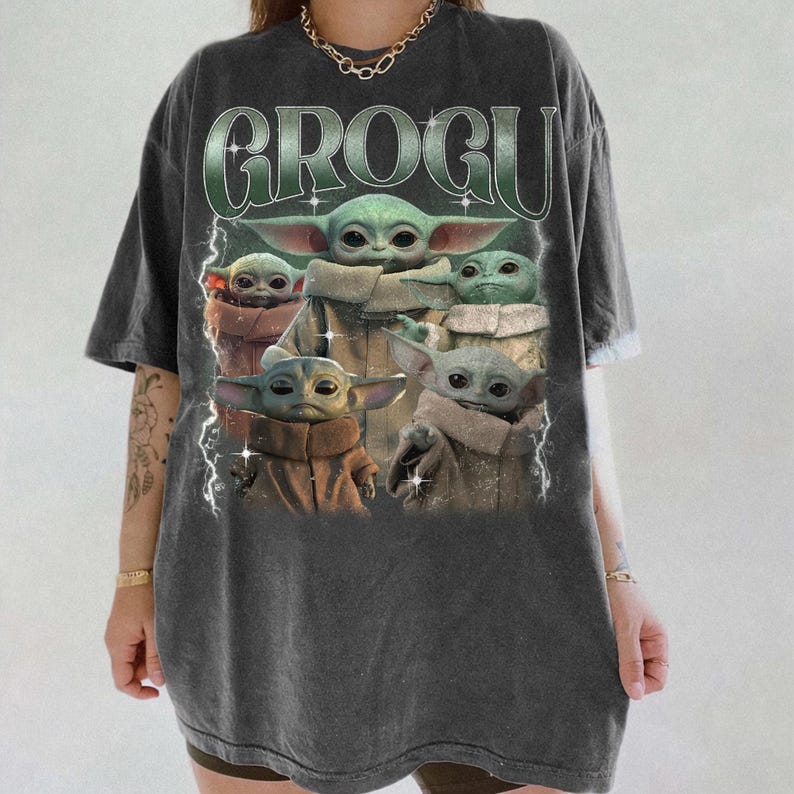 K&ouml;nnte beinhalten: Dunkelgraues T-Shirt mit einer Grafik von Grogu, auch bekannt als Baby Yoda, und dem Wort "GROGU". Das Bild zeigt Grogu in verschiedenen Posen. Das T-Shirt hat einen Vintage-Look.