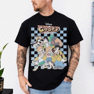 May include: Black t-shirt featuring a colorful graphic from Disney's "A Goofy Movie." The design includes Goofy and other characters in front of a checkered background with the movie title. The shirt is a classic crew neck.