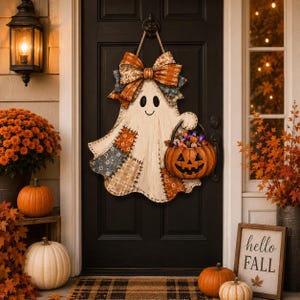 May include: A wooden ghost-shaped door hanger featuring a large plaid bow at the top, patchwork-style fabric patterns in blue and orange, and a hand holding a carved orange pumpkin bucket filled with colorful wrapped candies and treats.