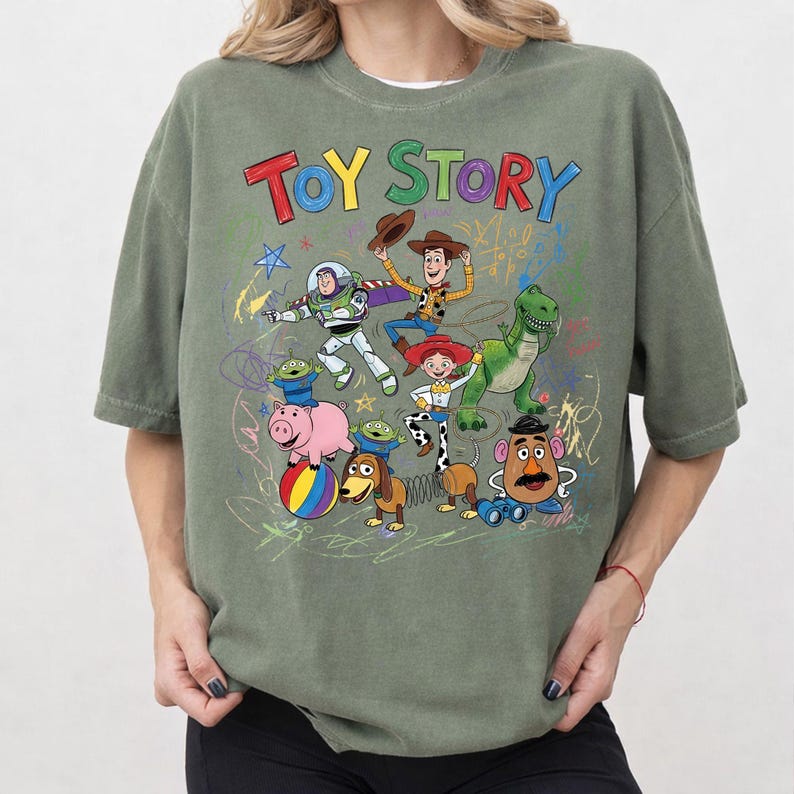 Puede incluir: Camiseta verde oliva con las palabras "TOY STORY" en letras coloridas. La camiseta presenta un gr&aacute;fico de personajes de la pel&iacute;cula animada, incluyendo a Woody, Buzz Lightyear y Rex.