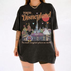 May include: Black t-shirt with a distressed graphic of Tokyo Disneyland. The design includes the park's castle, Mickey Mouse, and the text "Tokyo Disneyland" and "The most magical place on earth."