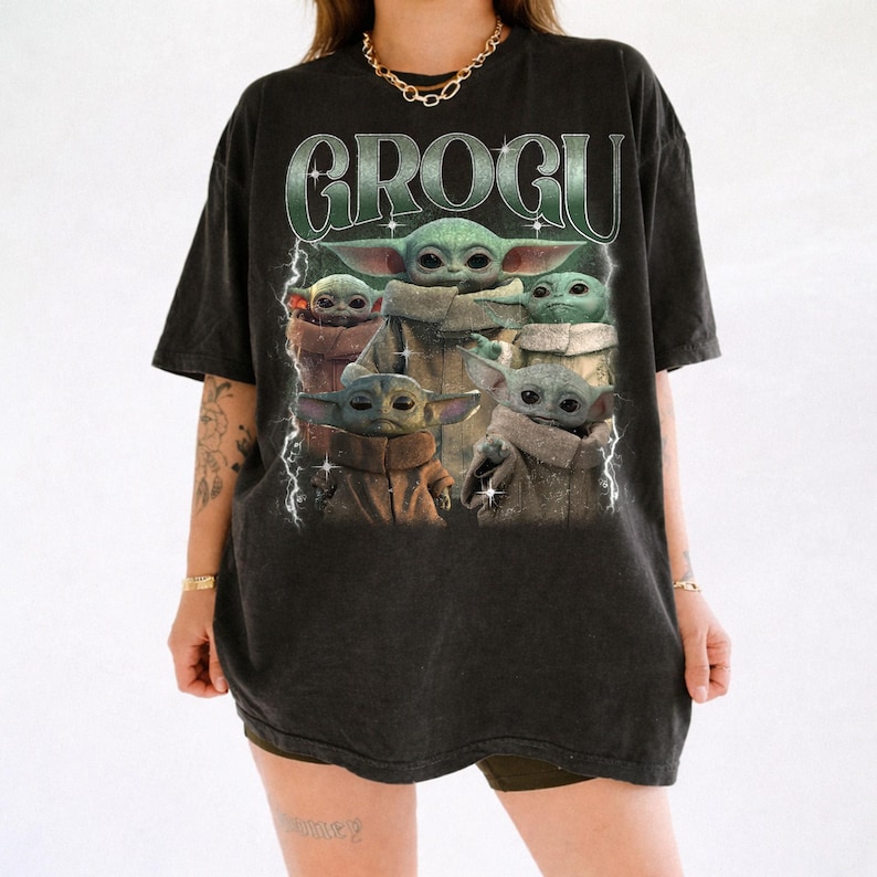 K&ouml;nnte beinhalten: Schwarzes T-Shirt mit einem Aufdruck von Grogu, auch bekannt als Baby Yoda, aus The Mandalorian. Das Design zeigt mehrere Bilder von Grogu mit dem Wort "GROGU" in einer gr&uuml;nen, verwitterten Schriftart. Das T-Shirt hat einen Vintage-Look.