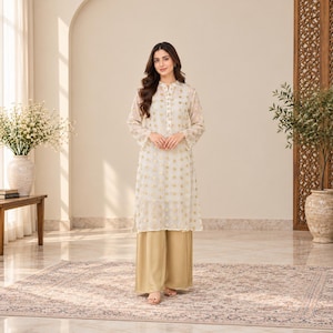 May include: A long-sleeved, off-white tunic featuring a repeating gold geometric pattern, a mandarin collar, and a button-down front placket, paired with solid gold-coloured wide-leg trousers that reach the floor in a straight-cut silhouette.