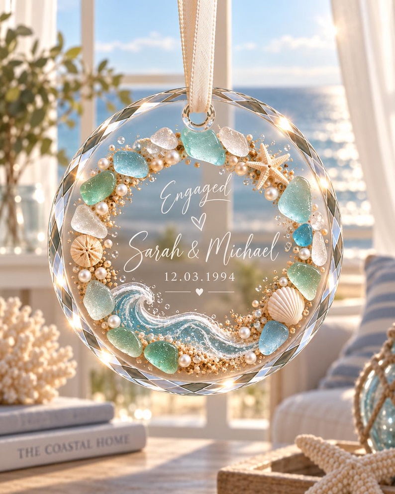 K&ouml;nnte beinhalten: Ein kreisf&ouml;rmiges Glasornament mit facettiertem Rand, verziert mit Meerglas, Perlen, einem Seestern und einer Muschel. Der Text lautet Engaged, Sarah & Michael, 12.03.1994, erg&auml;nzt durch eine Wellenillustration im unteren Bereich.