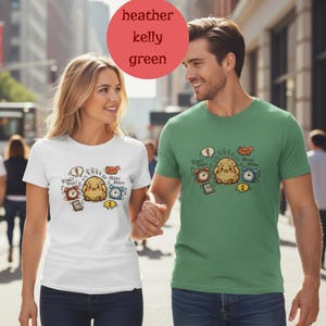 May include: A couple wearing matching t-shirts with a cartoon design. The shirts feature a distressed cartoon character surrounded by alarm clocks, speech bubbles, and a cell phone. The text on the shirts includes "Ring! Ring!", "Beep! Beep!", and "1".