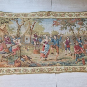Puede incluir: Un tapiz rectangular que representa una animada escena al aire libre con figuras vestidas con trajes de época. El tapiz presenta un borde detallado y un entorno pastoral con edificios, árboles y personas.