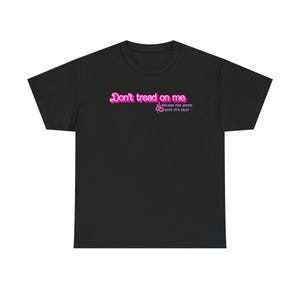 May include: Black t-shirt with the phrase "Don't tread on me" in pink, along with a pink snake graphic. Below the phrase is the text "Unless the news says it's heat".