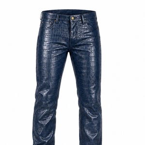Puede incluir: Un pantalón azul oscuro con un patrón texturizado de piel de cocodrilo en toda la prenda. El pantalón incluye un cierre de botón estándar en la cintura, trabillas para cinturón y un diseño clásico de cinco bolsillos con remaches metálicos.