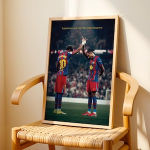 May include: Framed print featuring two soccer players in blue and red uniforms, high-fiving on a green field. The print has the text: "Superheroes are real. They wear blaugrana."