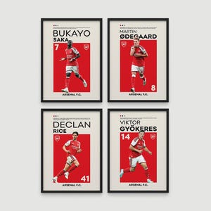May include: Four framed posters featuring Arsenal F.C. players Bukayo Saka, Martin Ødegaard, Declan Rice, and Viktor Gyökeres. Each print displays the player's name, jersey number, the Arsenal crest, and a red background with a white border.