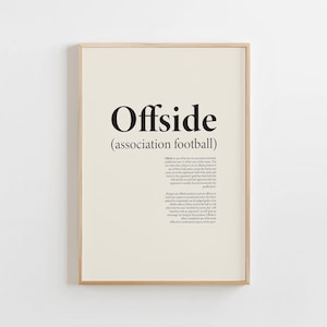 Puede incluir: Un póster enmarcado con la palabra "Offside" en negrita negra, con "(association football)" debajo. El fondo es de color beige claro y el marco es de color madera clara. Debajo del título hay una descripción del término.