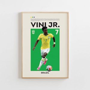 May include: A framed poster featuring a footballer in a yellow jersey with the number 7, white shorts, and white socks, dribbling a football on a green background. The text VINI JR. and BRAZIL is printed in black, with a small biographical paragraph.
