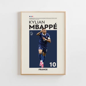 Puede incluir: Un póster enmarcado con una fotografía de Kylian Mbappé con la equipación de fútbol azul oscuro de Francia y botas rosas. El diseño incluye el texto Kylian Mbappé, el número 10, la palabra France, una pequeña bandera francesa y un emblema de gallo.