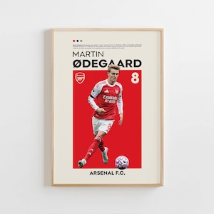 May include: A framed poster featuring Martin Ødegaard in an Arsenal F.C. uniform. The poster has a red and white color scheme with the number 8 prominently displayed. The player is shown with a soccer ball.