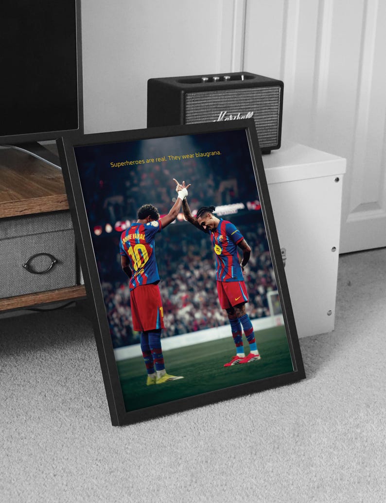 May include: Framed print featuring two soccer players in blue and red uniforms, high-fiving on a green field. The print includes the text "Superheroes are real. They wear blaugrana."