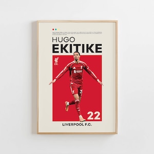 May include: Framed poster of Hugo Ekitike in a red Liverpool F.C. jersey, number 22. The poster has a red background with the player's name in large, bold letters. The Liverpool F.C. logo is also visible.