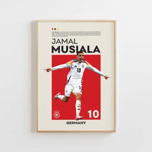 Puede incluir: Póster enmarcado de Jamal Musiala con uniforme de fútbol blanco y negro, número 10. El póster tiene un fondo rojo con la palabra "GERMANY" en la parte inferior. El nombre "JAMAL MUSIALA" está en la parte superior, con texto encima.