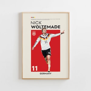 Puede incluir: Póster enmarcado con Nick Woltemade, futbolista alemán, con una camiseta blanca y negra con el número 11. El póster tiene un fondo rojo con la palabra "GERMANY" en la parte inferior.