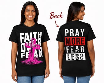 Op de afbeelding: Een zwart t-shirt met korte mouwen en een afbeelding op de voorkant met de witte tekst FAITH OVER FEAR en een roze kruis. De achterkant van het shirt toont de witte tekst PRAY, FEAR, LESS en de rode tekst MORE, met een rode pijl.