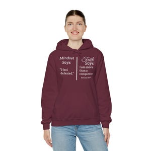 A woman wearing a maroon hoodie with text on it.