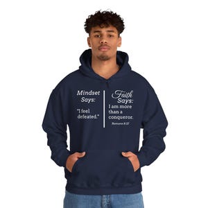 A man wearing a navy blue hoodie with text printed on it.