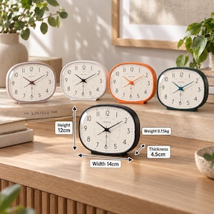 May include: Five oval analog clocks with white faces and black numerals, labeled Honey Time. The front clock is black, measuring 12 cm high, 14 cm wide, and 4.5 cm thick, weighing 0.15 kg. Other clocks are lavender, white, orange, and dark green.