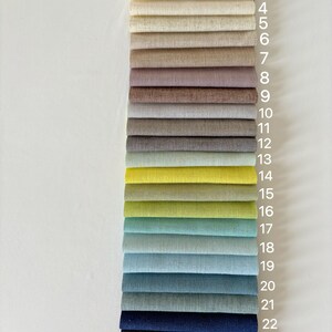 May include: A selection of 24 fabric swatches in a vertical arrangement, numbered 1 to 24. The colour palette includes shades from pale yellow and blush pink to navy and burgundy. Each swatch is a folded rectangle, displaying the fabric's texture.