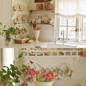May include: A light and airy kitchen with white shelves displaying decorative plates and cups. A white vase holds pink tulips, and a window with a white curtain is in the background. A basket and a painting are also visible.