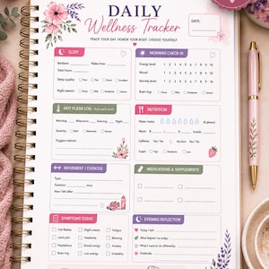 Może przedstawiać: Strona planera Daily Wellness Tracker w oprawie spiralnej z kwiatowymi akcentami. Sekcje obejmują sen, poranny check-in, dziennik uderzeń gorąca, odżywianie, ruch, leki, objawy i wieczorną refleksję. Tekst zawiera "Daily Wellness Tracker" oraz "Menopause Wellness & Hormone Health Planner". Strona ma wymiary 21,59 cm na 27,94 cm.