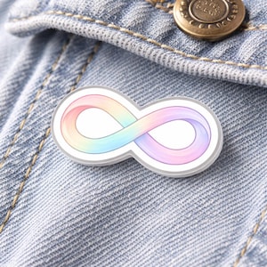 May include: A rainbow-coloured infinity symbol pin with a white border, displayed on a denim jacket. The pin showcases a gradient of colours, including pink, blue, yellow, and purple, in a continuous loop design.