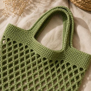 Close-up macro detail of handmade crochet mesh tote bag showing intricate stitch texture, open mesh design, sturdy crochet handle, and realistic cotton yarn detail.