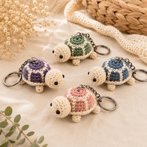 Peut inclure: Quatre porte-clés tortues au crochet avec des têtes et des membres couleur crème et des carapaces vertes, violettes, bleues et roses. Chaque tortue a des yeux en perles noires et est fixée à une chaîne en métal foncé et un anneau.