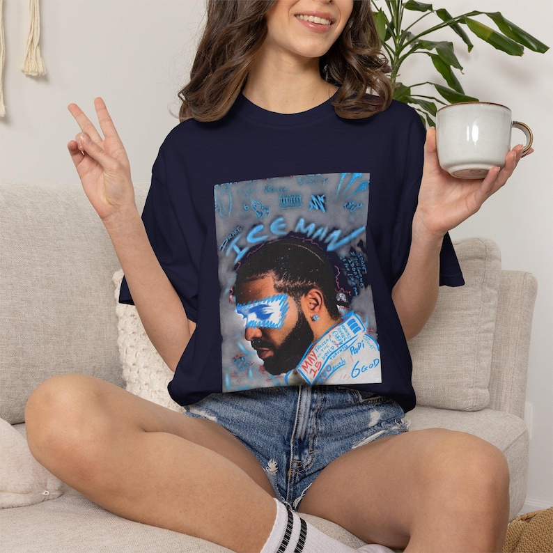 Puede incluir: Una camiseta azul marino con un estampado gr&aacute;fico de un hombre con barba y una m&aacute;scara azul en forma de rayo sobre los ojos. El texto "ICEMAN" est&aacute; impreso en azul sobre el retrato, con detalles de estilo manuscrito y acentos azules.