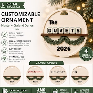 Puede incluir: Un adorno circular personalizable con una base de color crema, un estante horizontal marrón oscuro y detalles de guirnaldas verdes. El adorno muestra el texto The DUVETS y 2026, con opciones de diseño adicionales que incluyen Merry Christmas y On the Nice List.